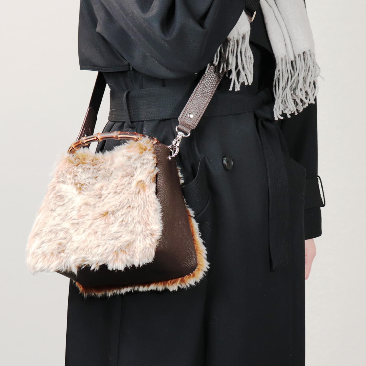 冬コーデに合わせた本革×グラデーションファーの2WAYミニトート【HOLLY・WEEKEND】を手に持つ女性。竹ハンドルが大人カジュアルを上品に見せるHANEANT KOBEのレザーバッグ。